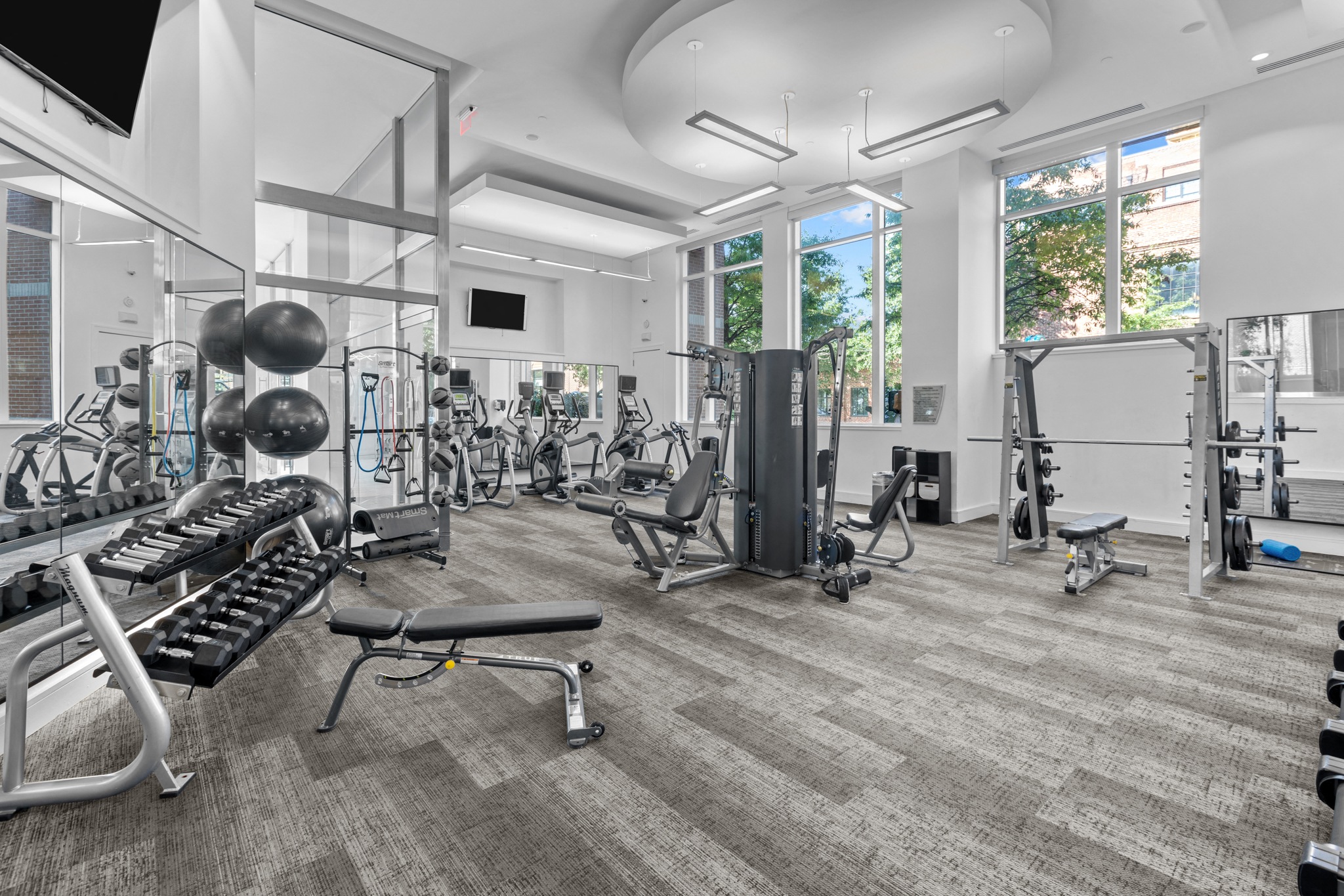 a gym with weights and cardio equipment and windows